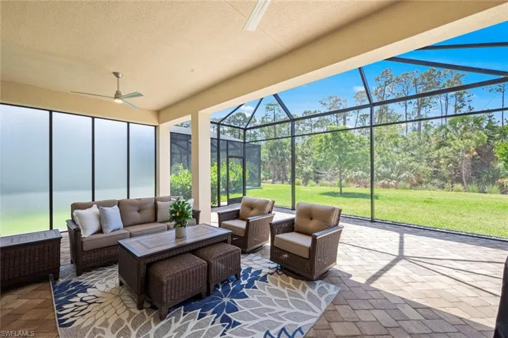 View of patio featuring glass enclosure, ceiling fan, and an outdoor living space