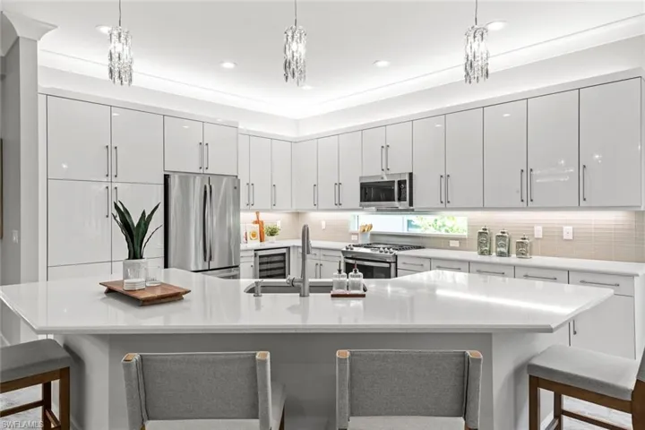 Kitchen with decorative backsplash, a breakfast bar area, decorative light fixtures, appliances with stainless steel finishes, and modern cabinets