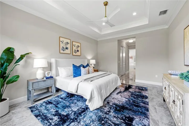 Bedroom featuring ornamental molding, visible vents, a raised ceiling, and baseboards