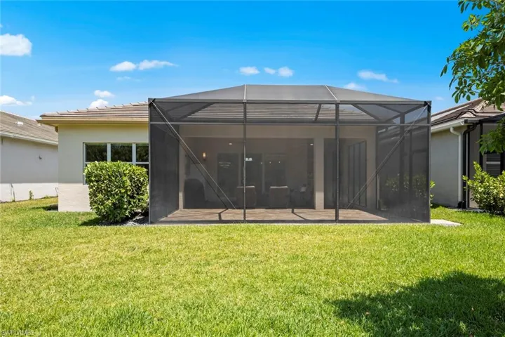 Rear view of house featuring stucco siding, a tiled roof, a patio, a lanai, and a lawn