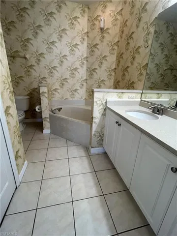 Full bath featuring wallpapered walls, a bath, light tile patterned floors, and vanity