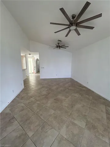 Spare room featuring vaulted ceiling, arched walkways, ceiling fan, and light tile patterned flooring