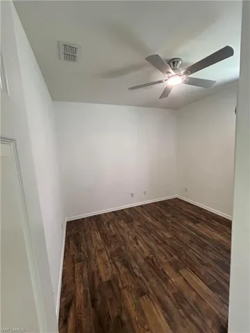 Unfurnished room with dark wood-style flooring and a ceiling fan
