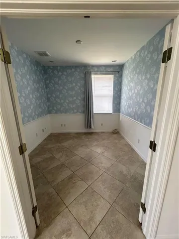 Empty room with light tile patterned floors and wallpapered walls