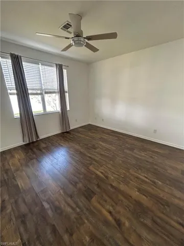 Spare room featuring dark wood-style flooring and a ceiling fan