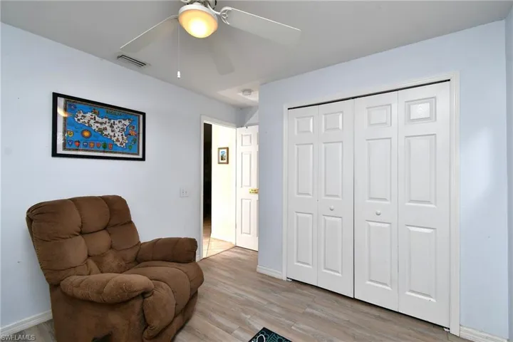 This room features light blue walls, light-colored wood-style flooring, and a ceiling fan