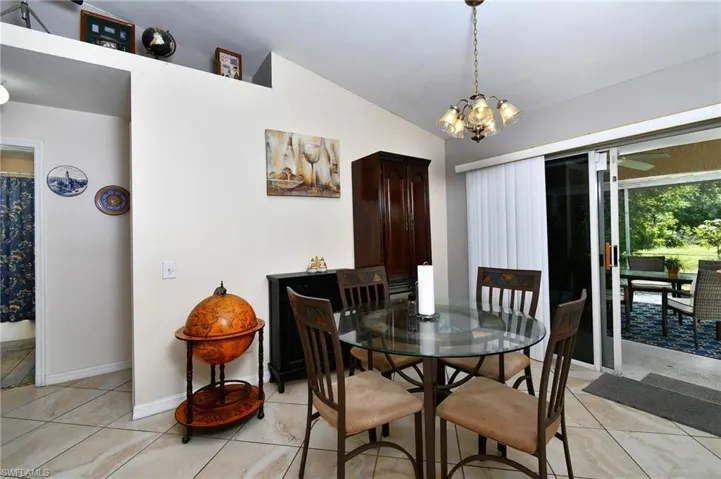 Dining area featuring tiled flooring, a decorative chandelier, and sliding glass doors leading to an outdoor screened patio