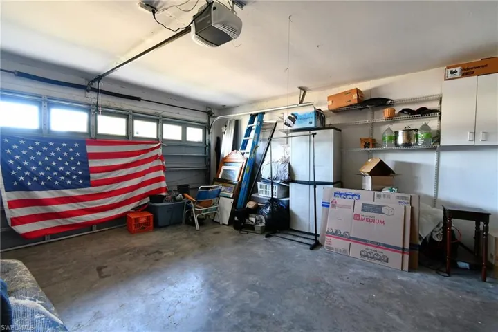 The garage features a concrete floor, a garage door with window inserts, and overhead lighting