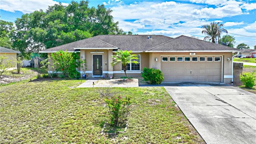 The property features a single-story design with a tan exterior, a dark roof, and an attached two-car garage