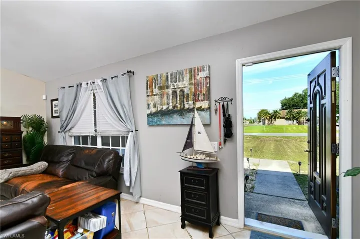 The property features a main entrance with a decorative dark wood door and a window, opening to a paved path and an expanse of green lawn