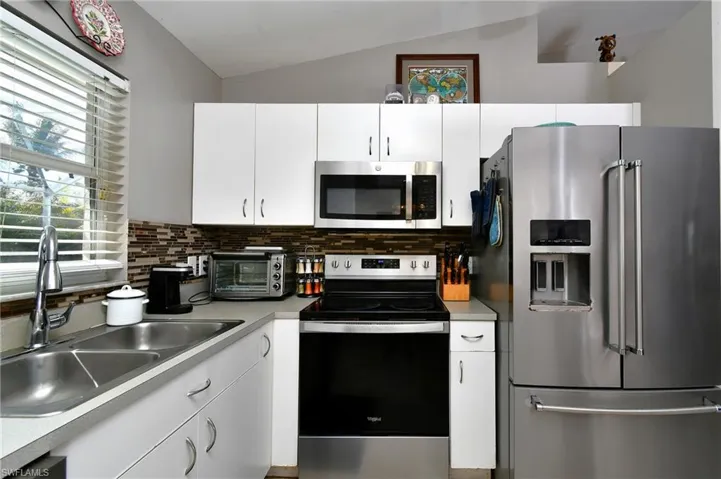 The kitchen features a stainless steel refrigerator, microwave, and range, complemented by white cabinetry and a tiled backsplash
