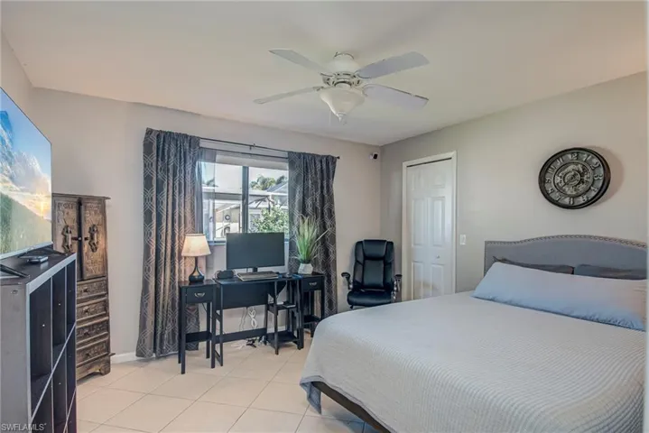 Bedroom featuring light tile patterned flooring, a closet, ceiling fan, and an office area