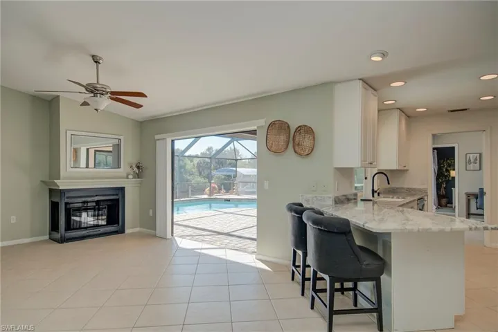 Kitchen with a kitchen breakfast bar, light stone countertops, light tile patterned flooring, a sunroom, and a peninsula