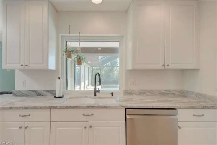 Kitchen featuring white cabinets, dishwasher, and light stone counters