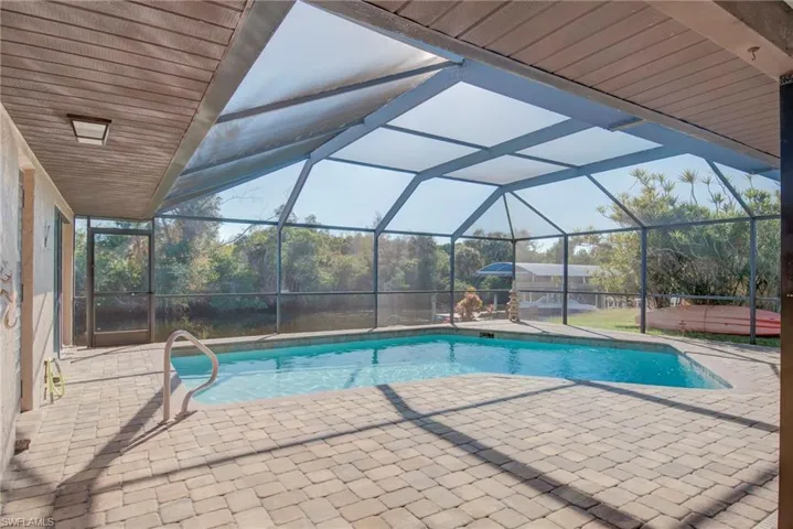Swimming pool featuring glass enclosure, a sunroom, and a patio