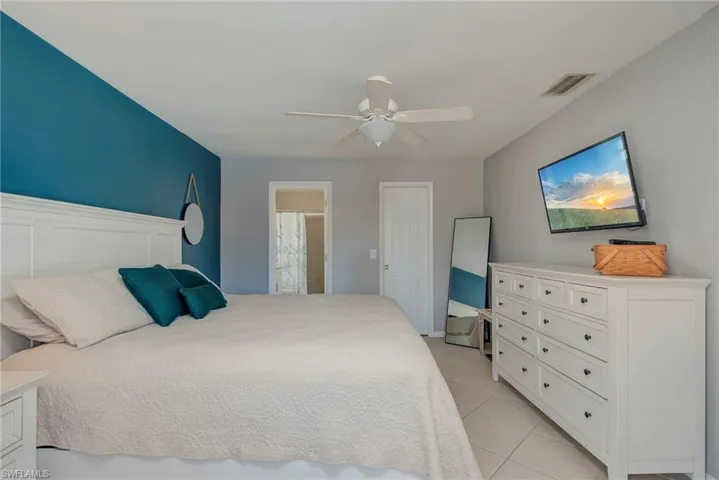 Bedroom with a ceiling fan, light tile patterned flooring, and ensuite bathroom