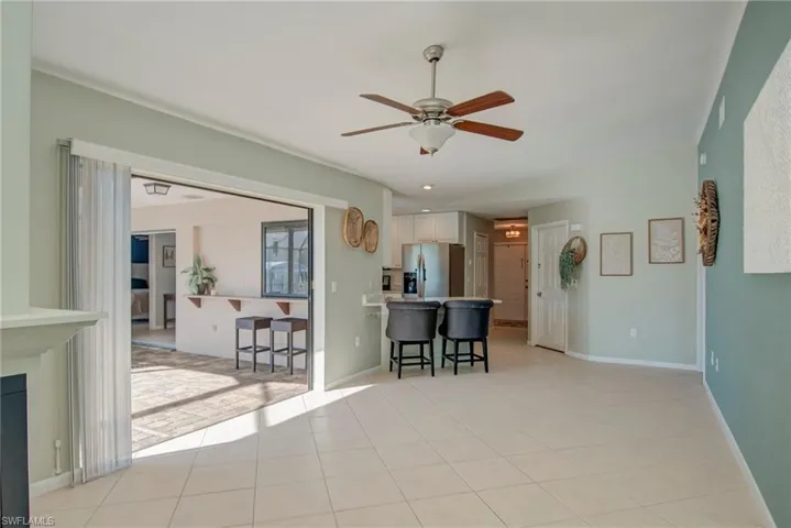 Living room with ceiling fan, light tile patterned flooring, and recessed lighting