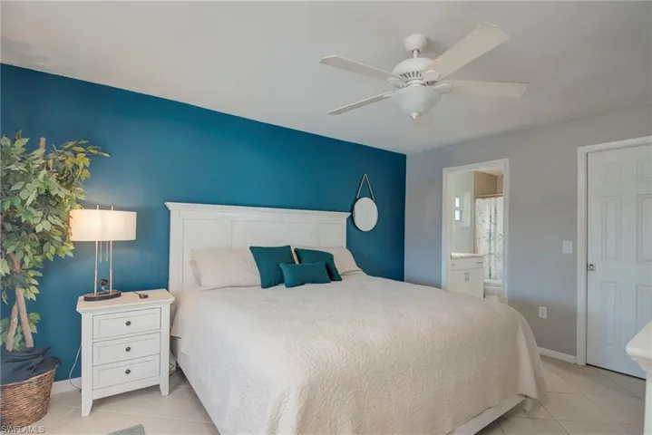 Bedroom with a ceiling fan, light tile patterned flooring, and ensuite bath