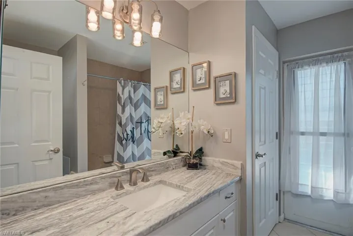 Bathroom with vanity, a shower with shower curtain, and light tile patterned flooring