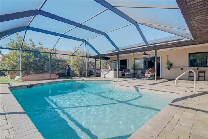 Swimming pool featuring a jacuzzi, a lanai, a sunroom, and a patio area
