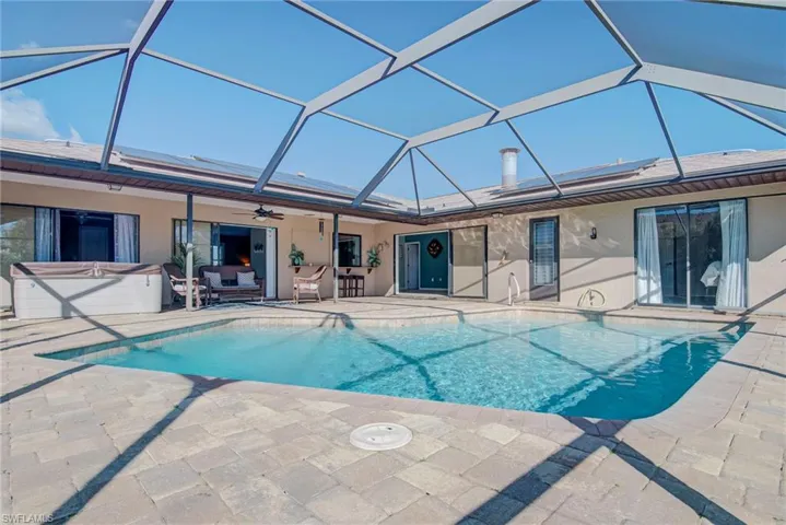Swimming pool with a hot tub, a sunroom, a patio area, and a lanai