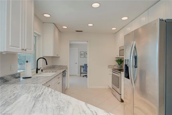 Kitchen with stainless steel appliances, light stone counters, white cabinetry, recessed lighting, and light tile patterned floors