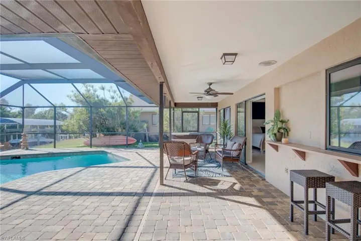 Outdoor pool with a hot tub, a patio, glass enclosure, and outdoor lounge area