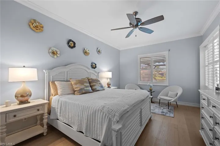 Bedroom featuring light wood-style floors, crown molding, and ceiling fan