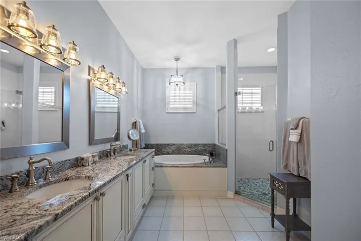 Bathroom featuring a stall shower, double vanity, a garden tub, light tile patterned floors, and recessed lighting