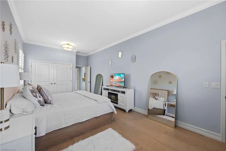 Bedroom with crown molding, light wood-type flooring, and a closet