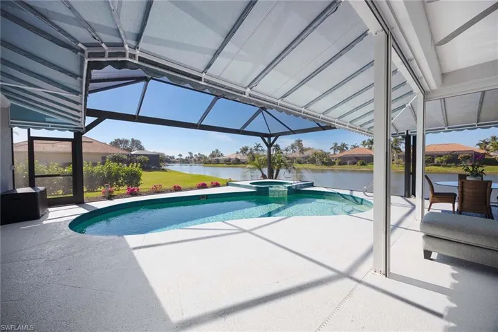View of swimming pool featuring a lanai, a residential view, a sunroom, a pool with connected hot tub, and a water view
