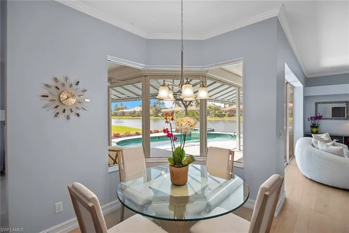 Dining space featuring crown molding, wood finished floors, a chandelier, and a water view