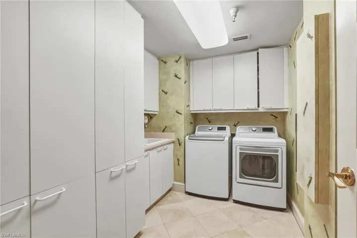 Laundry room with cabinet space, washer and clothes dryer, and light tile patterned floors