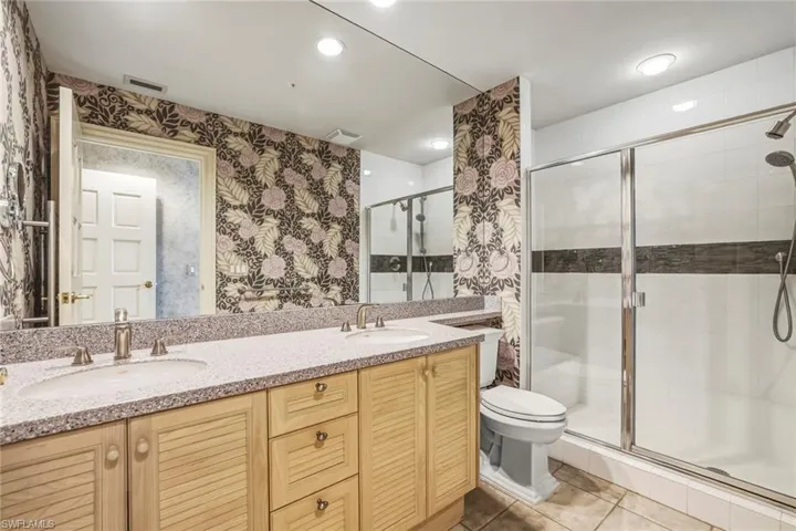 Bathroom with double vanity, a shower stall, recessed lighting, light tile patterned flooring, and wallpapered walls