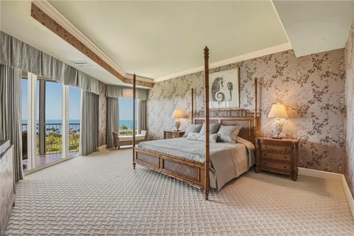 Bedroom featuring crown molding, a water view, light colored carpet, access to exterior, and wallpapered walls