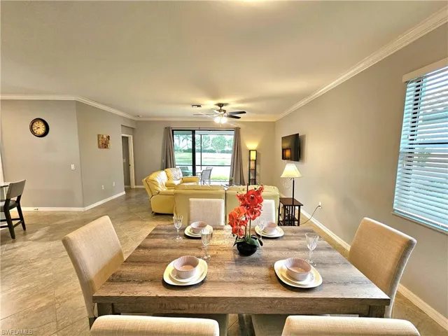 Tiled dining space featuring ceiling fan and crown molding