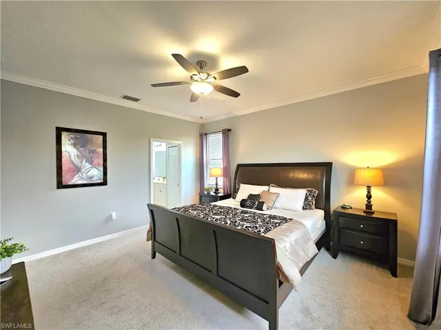 Bedroom featuring ensuite bath, ceiling fan, crown molding, and light carpet