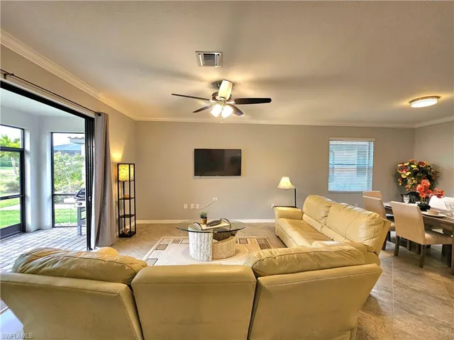 Tiled living room featuring ceiling fan and ornamental molding