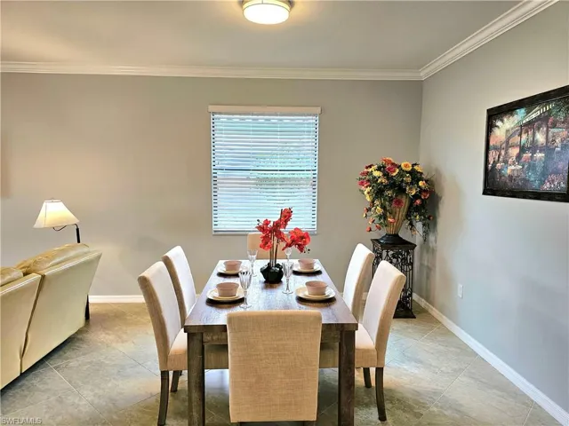 Dining space featuring light tile patterned floors and crown molding