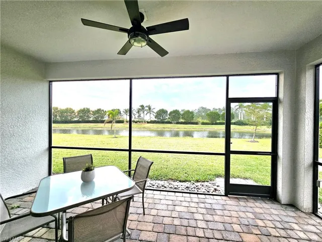 Sunroom / solarium featuring ceiling fan and a water view