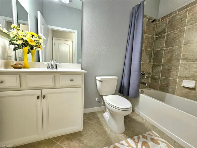 Full bathroom featuring tile patterned floors, shower / bath combo, toilet, and vanity