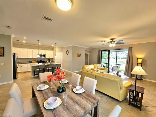 Dining area featuring ceiling fan, ornamental molding, and light tile patterned flooring