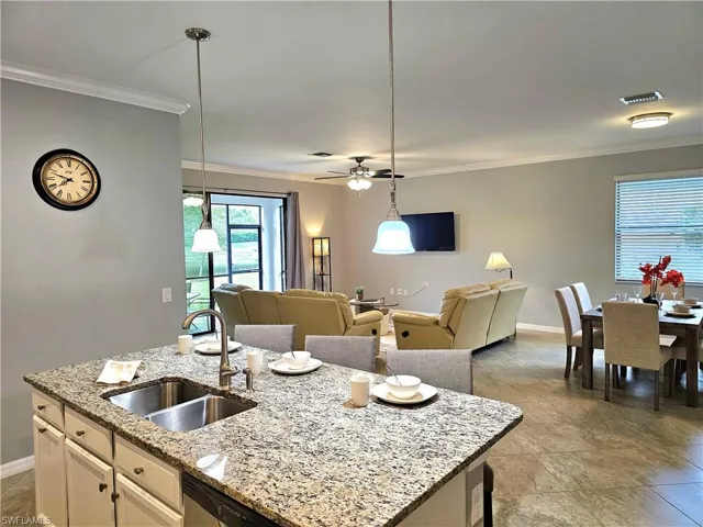 Kitchen featuring sink, white cabinets, decorative light fixtures, and a center island with sink