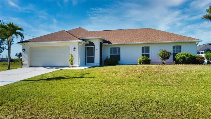 Single story home featuring stucco siding, concrete driveway, a shingled roof, and a front yard