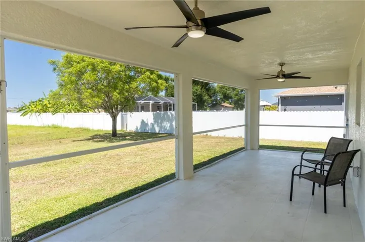 Unfurnished sunroom with ceiling fan and a patio area