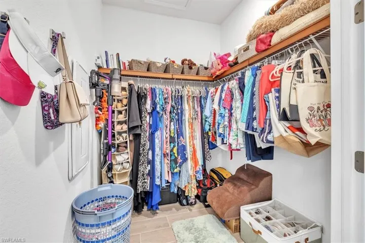 Walk-in closet featuring built-in shelving, hanging rods, and light-toned flooring