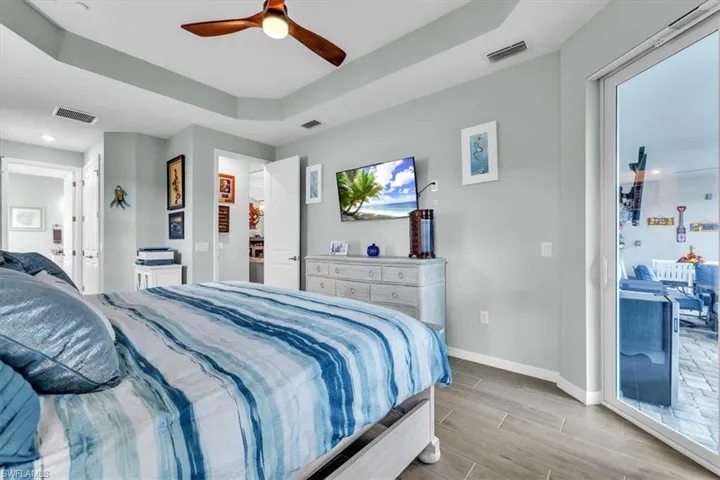 Tray ceiling with a wood-finish ceiling fan, light gray wall paint, and wood-finish flooring