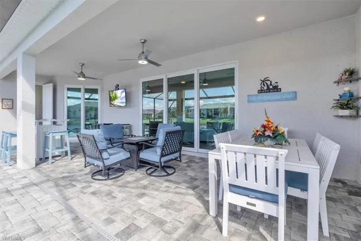 Expansive covered patio featuring paver flooring, multiple ceiling fans, recessed lighting, and large sliding glass doors