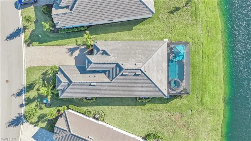 Property featuring a tiled roof, screened swimming pool, and a paved driveway