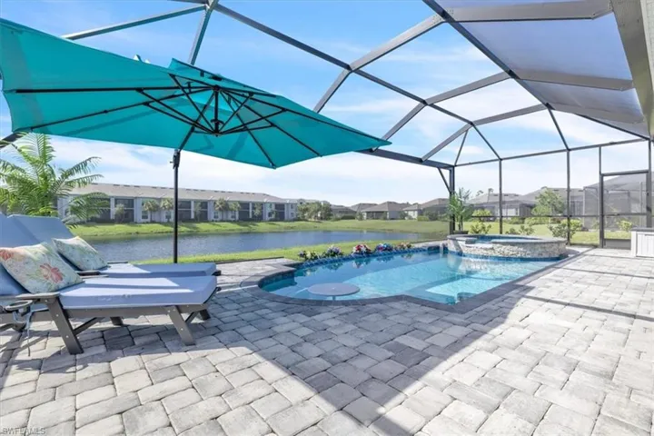 Screened lanai featuring a swimming pool, integrated spa with stone surround, and paver patio